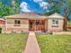 Charming brick home with a covered front porch, lush lawn, and neatly landscaped flower beds at 1600 Xanthia St, Denver, CO 80220