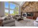 Inviting living room with stone fireplace, large windows, and comfortable seating area at 6299 Ellingwood Point Pl, Castle Rock, CO 80108