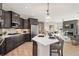 Open concept kitchen with dark cabinets, stainless steel appliances, island and adjacent living area at 359 Josef Cir, Fort Lupton, CO 80621