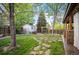 Beautiful backyard with a shed, stone pathway, stone accents, and mature trees at 6480 Moss Cir, Arvada, CO 80007