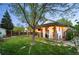 Beautiful backyard with stone pathway leading to covered patio with lights and curtains at 6480 Moss Cir, Arvada, CO 80007