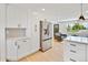 Kitchen with stainless steel refrigerator, white cabinetry, and view into the living room at 7826 Joan Dr, Denver, CO 80221