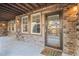Covered stone patio featuring a glass door, windows, and a 