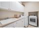 Well-organized laundry room with a utility sink, washer, dryer, and white cabinets at 24273 E Fremont Dr, Aurora, CO 80016