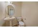 Cozy half-bathroom featuring a pedestal sink, round mirror, and toilet at 6393 S Richfield St, Aurora, CO 80016