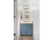 This half bathroom features a blue vanity with modern fixtures and a decorative mirror at 8738 Chase Dr # 133, Arvada, CO 80003