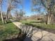 Concrete path surrounded by green grass and scattered trees under a clear blue sky, shadow in foreground at 4505 Everett St, Wheat Ridge, CO 80033