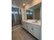 Bathroom with double sinks, white vanity, and a glass-enclosed shower with tile surround at 8840 Whiteclover St, Littleton, CO 80125