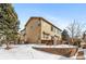 Two-story home with light brown siding, snowy yard, and brick retaining wall at 3953 Blue Pine Cir, Highlands Ranch, CO 80126