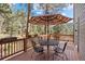 Relaxing deck space with outdoor dining set and umbrella, surrounded by lush greenery and a peaceful setting at 6904 Sprucedale Park Way, Evergreen, CO 80439