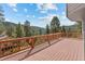 Expansive deck showcasing wooden railings and scenic views of the surrounding forest and mountain landscape at 6904 Sprucedale Pkwy, Evergreen, CO 80439