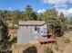 Multi-level grey home with a deck, surrounded by trees at 6904 Sprucedale Pkwy, Evergreen, CO 80439