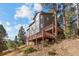 View of the home's exterior and deck, surrounded by trees at 6904 Sprucedale Pkwy, Evergreen, CO 80439