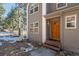 Charming home with a covered front porch, a stained wood door and views of mature trees at 6904 Sprucedale Pkwy, Evergreen, CO 80439