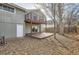 A spacious backyard features a door to the basement, a wood fence, trees, and an upper deck at 9551 E Chenango Ave, Greenwood Village, CO 80111