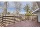 An outdoor deck has wood flooring, and brown railings with a view of the surrounding trees at 9551 E Chenango Ave, Greenwood Village, CO 80111