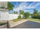 Backyard featuring a white fence, a grassy area, mature trees and access to a detached garage at 291 Magnolia St, Denver, CO 80220