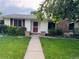 Close-up of a single-story home featuring a brick accent wall, red door, and green lawn at 291 Magnolia St, Denver, CO 80220