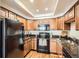 Bright kitchen with wooden floors, stainless steel sink, and black appliances including refrigerator, microwave and oven at 701 Harlan St # E59, Lakewood, CO 80214
