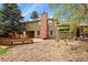 Wide shot of backyard with a wooden deck, brick chimney, and mulch at 7376 S Jackson St, Centennial, CO 80122