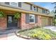 Close up of the beautiful home exterior featuring red brick, a dark double door, and colorful flower beds at 7376 S Jackson St, Centennial, CO 80122