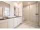 Bathroom featuring double sink vanity, framed mirrors, and large shower with glass door at 605 Twilight St, Erie, CO 80516
