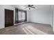 Bright living room with neutral carpet, ceiling fan, and a large window draped with elegant gray curtains at 7971 Olive St, Commerce City, CO 80022