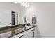 Well-lit bathroom featuring a granite countertop, white cabinets, and a mirrored wall at 89 Clara Pl, Castle Pines, CO 80108