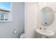 This powder room features a pedestal sink with a round mirror and bright natural light at 89 Clara Pl, Castle Pines, CO 80108