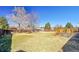 Wide backyard with large grassy area and mature trees and a wood deck at 1244 S Argonne Cir, Aurora, CO 80017