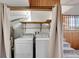 Bright laundry room featuring a stacked washer and dryer, shelving and wood accents at 1244 S Argonne Cir, Aurora, CO 80017