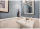 Stylish powder room with wainscoting, framed mirror, and elegant pedestal sink at 10472 Longleaf Dr, Parker, CO 80134