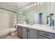 Bathroom features a white tub and shower, grey vanity, large mirror, and brushed bronze fixtures at 10472 Longleaf Dr, Parker, CO 80134