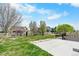 Beautiful backyard with green lawn, mature trees, and white picket fence under a blue sky at 9060 Ferncrest St, Firestone, CO 80504