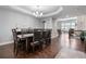 Elegant dining room featuring modern chandelier, tray ceiling, and dark hardwood flooring throughout at 9060 Ferncrest St, Firestone, CO 80504