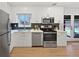 Modern kitchen features white cabinets, stainless appliances, black backsplash, and light wood floors at 9639 W 63Rd Pl, Arvada, CO 80004
