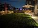 Large backyard at dusk with manicured lawn, patio seating, and landscape lighting creating a warm ambiance at 821 Boulder Peak Ave, Erie, CO 80516
