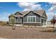 Charming gray home with white trim, stone accents, rock landscaping, and a three-car garage at 9915 E 162Nd Pl, Brighton, CO 80602