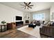 Cozy living room featuring a fireplace, ceiling fan, and large windows that provide an abundance of natural light at 9915 E 162Nd Pl, Brighton, CO 80602