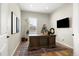 Home office with a large wooden desk, hardwood floors, and a wall-mounted TV at 9915 E 162Nd Pl, Brighton, CO 80602