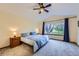 Bright main bedroom featuring a large window with views of the landscaped yard and a ceiling fan at 10963 Bryant St, Westminster, CO 80234