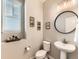 Modern powder room features a pedestal sink, round mirror, and stylish decorative elements at 11902 Norfolk Ct, Commerce City, CO 80022