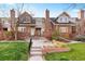 Attractive townhome featuring a well-maintained lawn, red brickwork, and inviting entrance at 443 Garfield St, Denver, CO 80206