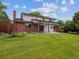 An expansive backyard is presented with a brick house, open patio, and large green space at 6898 W Nova Dr, Littleton, CO 80128