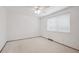 A bright bedroom is shown with a ceiling fan, large window, and neutral carpet at 6898 W Nova Dr, Littleton, CO 80128