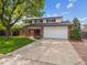 Beautiful two-story home with a brick facade, attached garage, and mature landscaping at 6898 W Nova Dr, Littleton, CO 80128
