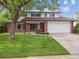 Charming two-story brick home with a well-manicured lawn and mature tree at 6898 W Nova Dr, Littleton, CO 80128