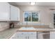 Kitchen sink with a window view, white cabinetry, and tile countertops with backsplash at 3186 W Indian Summer Ln, Castle Rock, CO 80109
