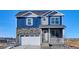 Charming two-story home with blue siding, stone accents, a two-car garage and covered front porch at 758 N Clubview St, Watkins, CO 80137