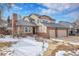 Inviting two-story home featuring Tudor-style accents, a brick chimney, and a spacious driveway with snow at 3575 S Waco St, Aurora, CO 80013